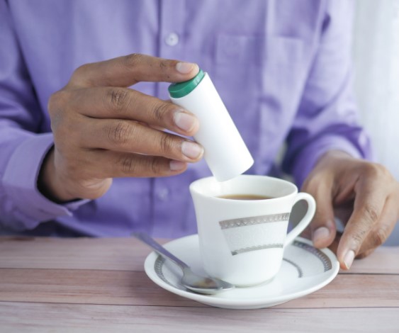 Woman using artificial sweeteners in a hot beverage